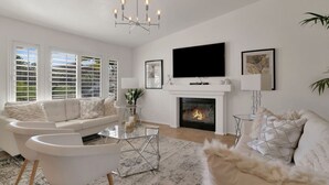 A modern living room with a fireplace, white furniture, and a large flat-screen TV. - 10 Bd/walk 2 shuttle 4 Stagecoach/Ask-Deals/Games (La Quinta)
