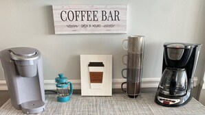 A coffee bar setup with a coffee maker, a mug, and a sign that reads "Coffee Bar". - Oceanfront Family Friendly Garden City Beach Condo (Murrells Inlet)