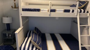 A bunk bed with striped bedding, a nightstand with a lamp, and a decorative anchor on the wall. - Oceanfront Family Friendly Garden City Beach Condo (Murrells Inlet)