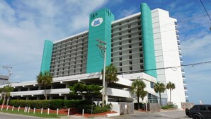 A hotel with a prominent sign, multiple floors, and a parking area. - Oceanfront Family Friendly Garden City Beach Condo (Murrells Inlet)