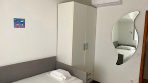 Un dormitorio con cama, armario, espejo y aire acondicionado.