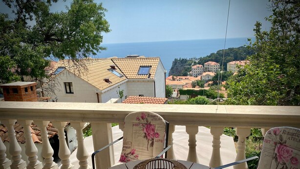 Un balcón con vistas a un pueblo costero, que incluye una lámpara decorativa y cojines florales.