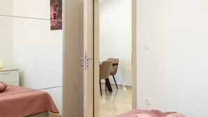 Une chambre à coucher comprenant un lit, une table de chevet, une armoire et une chaise dans la pièce adjacente.
