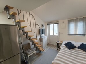 Ein kleines Schlafzimmer mit integriertem Bettstufenhaus, einem kleinen Schreibtisch und einem Kühlschrank.