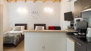 A modern bedroom with a wooden ceiling, a bed with a quilt, a bedside table, and a wall-mounted TV. - Apartments Roza - Studio Apartment (Mlini)