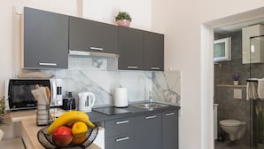 A modern kitchen with grey cabinets, a microwave, a kettle, and a fruit bowl. - Apartments Roza - Studio Apartment (Mlini)