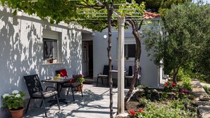 Eine Terrasse mit Tisch und Stühlen, einer Pergola und Topfpflanzen.