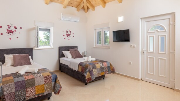 Ein Schlafzimmer mit zwei Betten, einer Holzbalkendecke und einer weißen Tür.