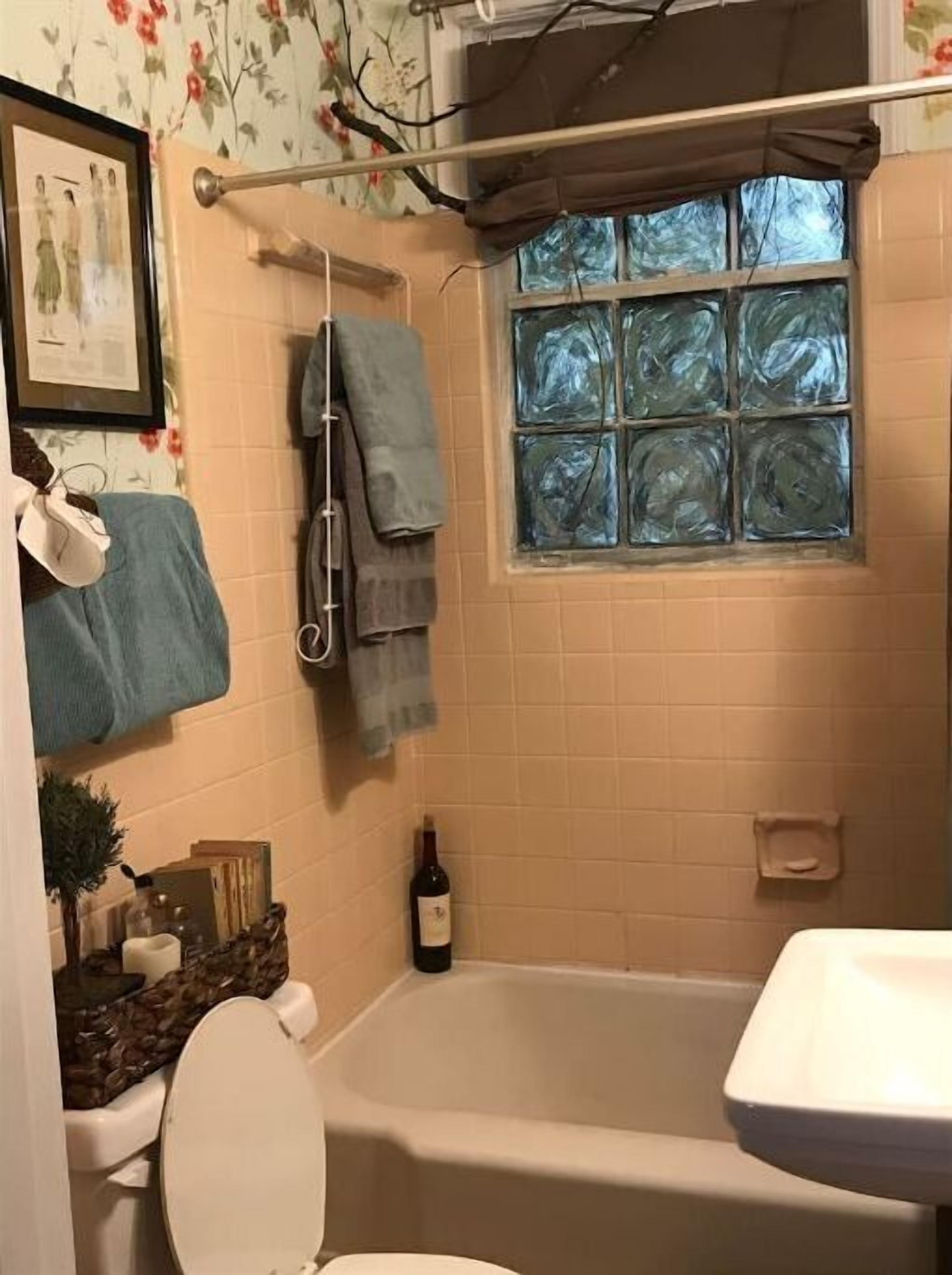 Une salle de bain avec une baignoire, des toilettes et une fenêtre donnant sur les arbres.
