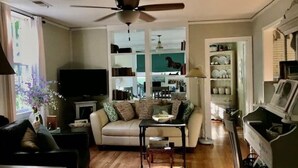 Ein Wohnzimmer mit einer Couch, einem Couchtisch, einem Fernseher und einem Deckenventilator.