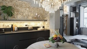 A modern kitchen with a stone backsplash, a chandelier, and a dining area with a table set for two. - Isonzo Suites (Syracuse)