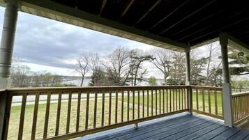 A covered porch with a view of a grassy yard and trees.