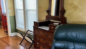 A room with a wooden dresser, a mirror, and a black leather chair. - Riverview Orchard 2: Master Suite Studio Style (Hamilton)