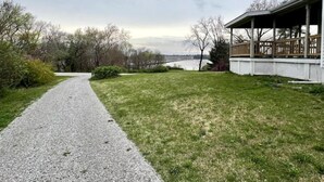 A gravel path leading to a covered porch with a view of a river and distant buildings. - Riverview Orchard 2: Master Suite Studio Style (Hamilton)