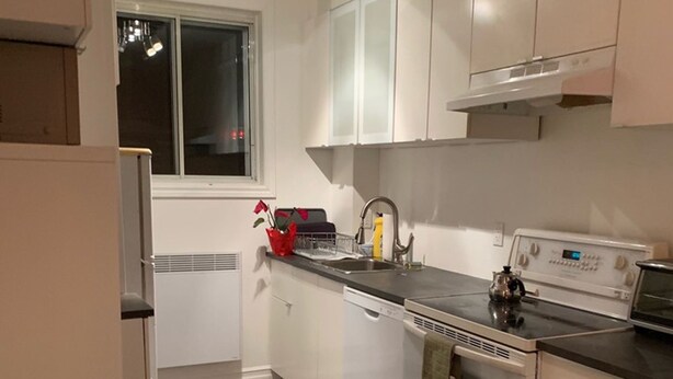 Una cocina moderna con armarios blancos, un lavamanos de acero inoxidable y un horno empotrado.