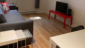 Una sala de estar moderna con un sofá gris, una mesa blanca y un mueble de televisión rojo.