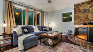 A cozy living room with a sectional sofa, a fireplace, and a patterned rug. - Dog Friendly, 3 Bedrooms, Hot Tub, Peaceful & Private, Mini Golf, Coffee Bar! (Sevierville)