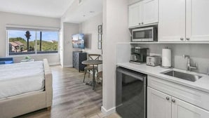 A modern kitchen with white cabinets, a microwave, a toaster, and a sink.