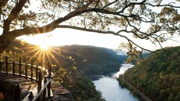 A scenic overlook with a river, a bridge, and a railing.