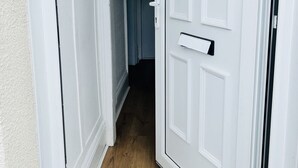 Una puerta blanca con manija, un pequeño ventanal encima y un timbre.