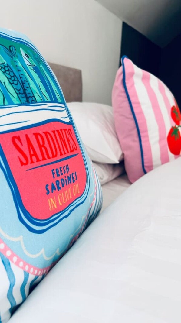 A bed with a blue and pink striped pillow and a pillow with a tomato design.