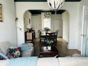 A living room with a sofa, coffee table, and a dining area with chairs and a chandelier.