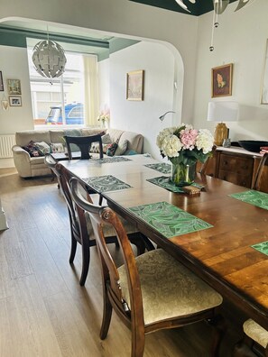 Un comedor con mesa de madera, sillas y un jarrón de flores.