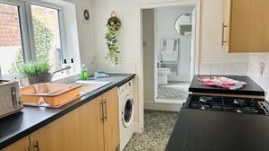 Una cocina con lavadora, estufa, tostadora y una ventana con plantas.