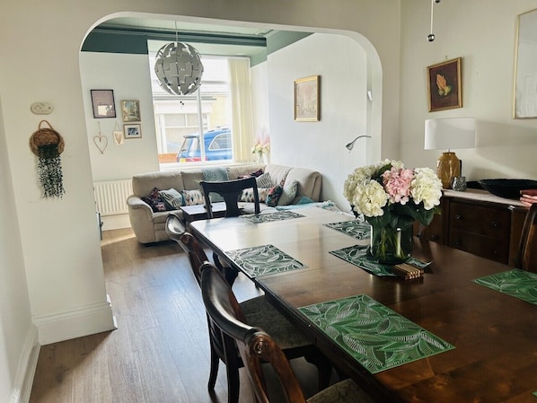 A dining area with a wooden table, chairs, and a vase of flowers.