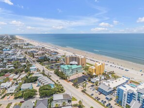 A coastal town with a beachfront hotel, a road, and a parking lot.