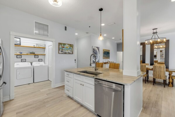 A modern kitchen with built-in appliances, a central island, and a dining area with wicker chairs.