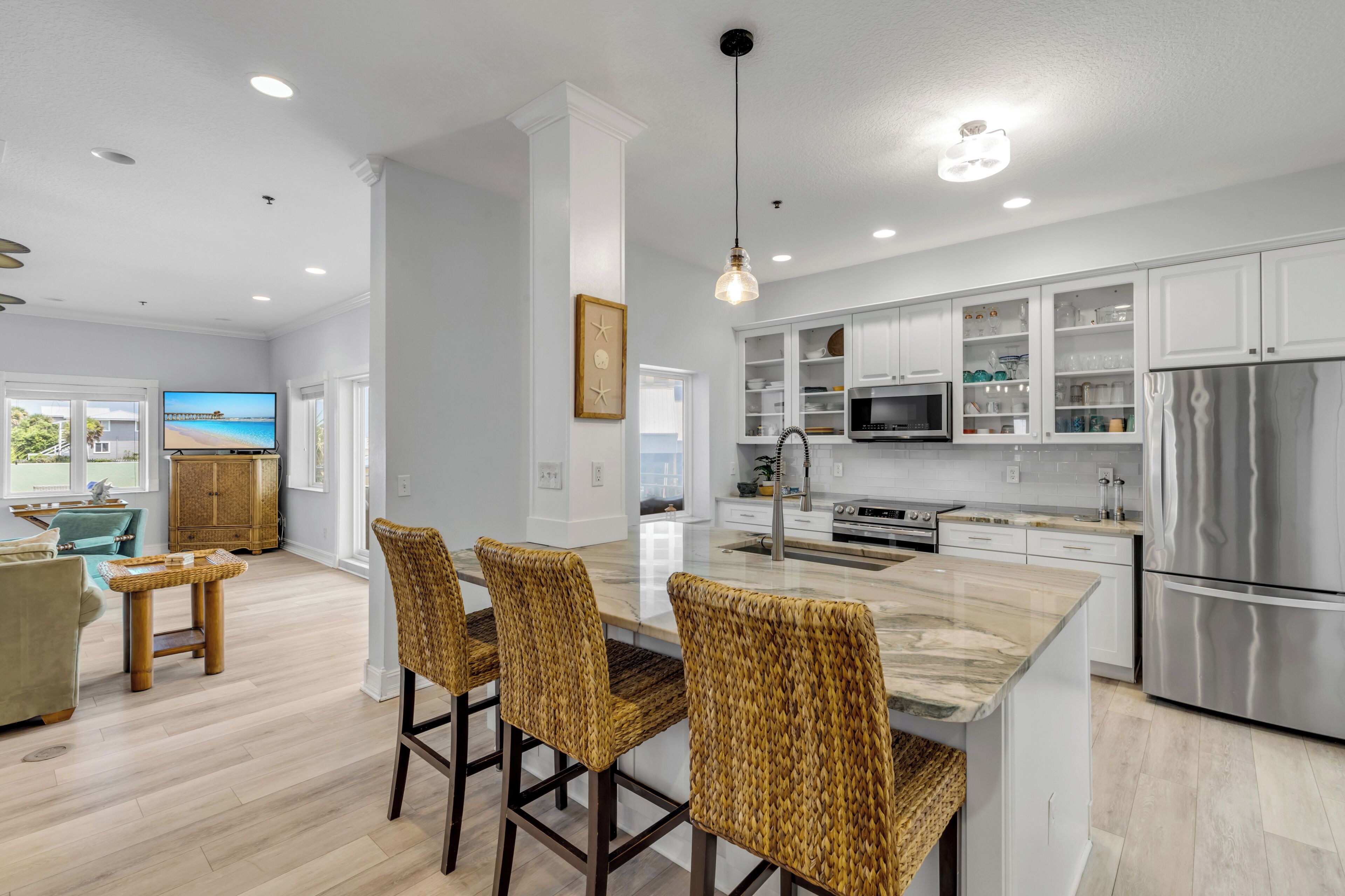 A modern kitchen with white cabinetry, stainless steel appliances, and a central island with bar stools.