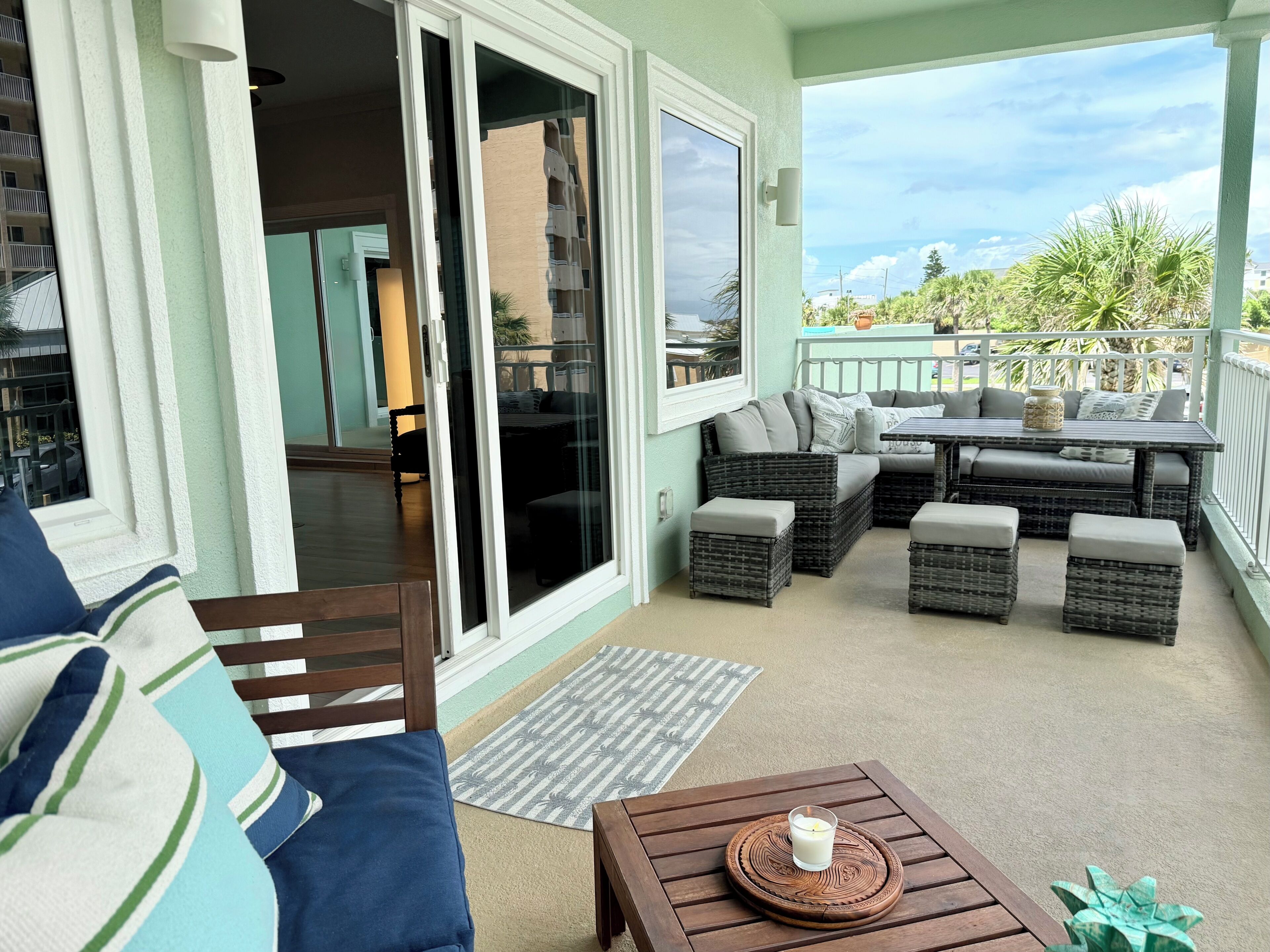Uma área de varanda coberta com um espaço de estar, uma mesa e vista para o exterior.