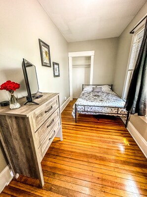 A bedroom with a wooden dresser, a bed with a patterned bedspread, a large mirror, and a window with blinds. - "The Red House" 4 Bedroom/Sleeps 8 in the heart of Albany NY (Albany)