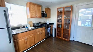 A kitchen with wooden cabinets, a stainless steel refrigerator, a microwave, and a stove. - Main St. Retreat (Safety Harbor)