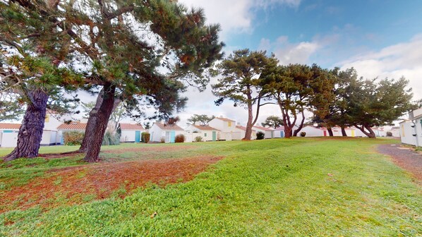 A grassy area with trees and white buildings with red roofs.