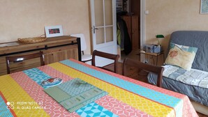 Ein Zimmer mit Esstisch, Stühlen, einem Bett und einem Kleiderschrank.