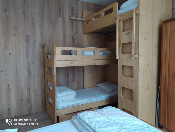 A bunk bed room with wooden walls and a door. - Appartement Lumineux Centre Bourg (Villard de Lans)