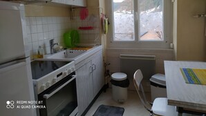 Eine kleine Küche mit weißen Schränken, einem eingebauten Backofen, einer Spüle und einem Fenster mit Blick auf eine verschneite Landschaft.