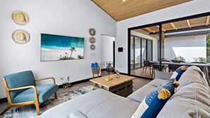 Een moderne woonkamer met een grote bank, een blauwe fauteuil en een houten plafond.