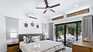 Een moderne slaapkamer met een groot bed, een plafondventilator en uitzicht op een buitenzwembad.