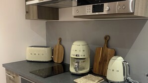 A modern kitchen with a built-in microwave, toaster, coffee maker, and dishwasher. - Le Pied à Terre N°3 (Grosseto-Prugna)
