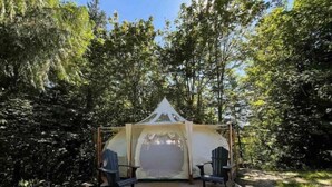 Un kiosque doté d’un toit transparent, de deux chaises et d’une terrasse en bois.