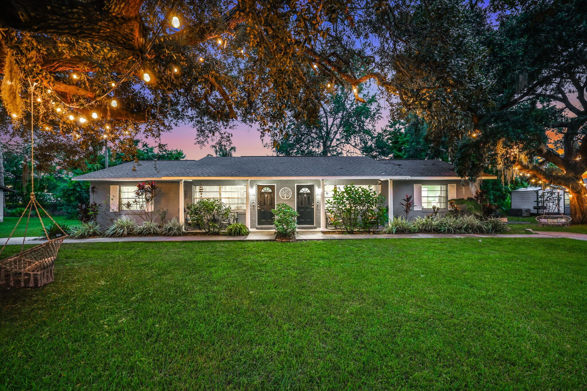 A house with a front porch, a well-maintained lawn, and string lights.