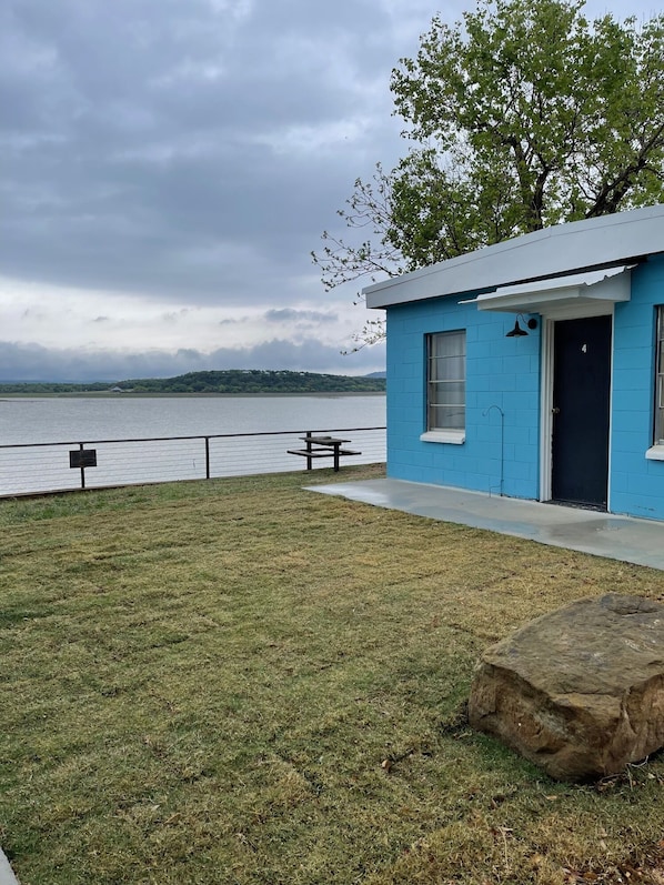 A small blue building with a door marked '4', a bench, and a grassy area in front.
