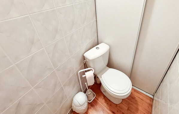 Ein kleines, sauberes Badezimmer mit Toilette, Toilettenpapierhalter und Bidet.