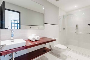 A modern bathroom with a white sink, a large mirror, a glass shower enclosure, and a toilet. - Casa Lefevre 3C (Panama City)