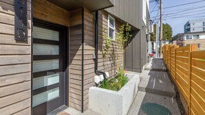 Un edificio moderno con fachada de madera, un macetero de hormigón con plantas y una valla de madera.