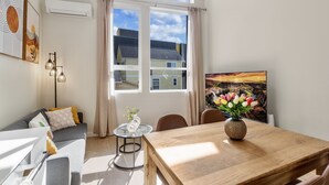 Una sala de estar moderna con un sofá, una mesa de comedor y vistas al exterior a través de amplios ventanales.