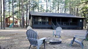 Uma cabana com varanda, área de estar externa e parquinho.